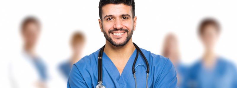Male nurse smiling in front of team of doctors