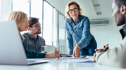 Female leader speaking in boardroom to staff-alt-text