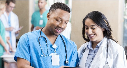 two healthcare workers, a male in scrub and a female in a white coat , both wearing stethescopes discussing a chart