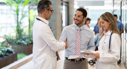 two male and one female healthcare worker discussing paperwork in a hospital hall
