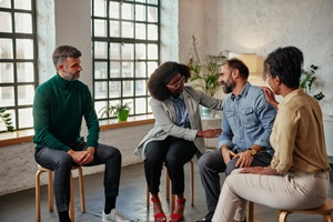 four people in a group therapy session listening and sharing