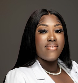 Charlene Coates headshot wearing a white jacket and pearls