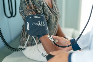 a medical professional is taking the blood pressure of a female patient in a patterned blouse