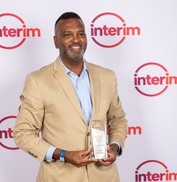 Waddie Freeman headshot wearing a tan suit holding a glass award