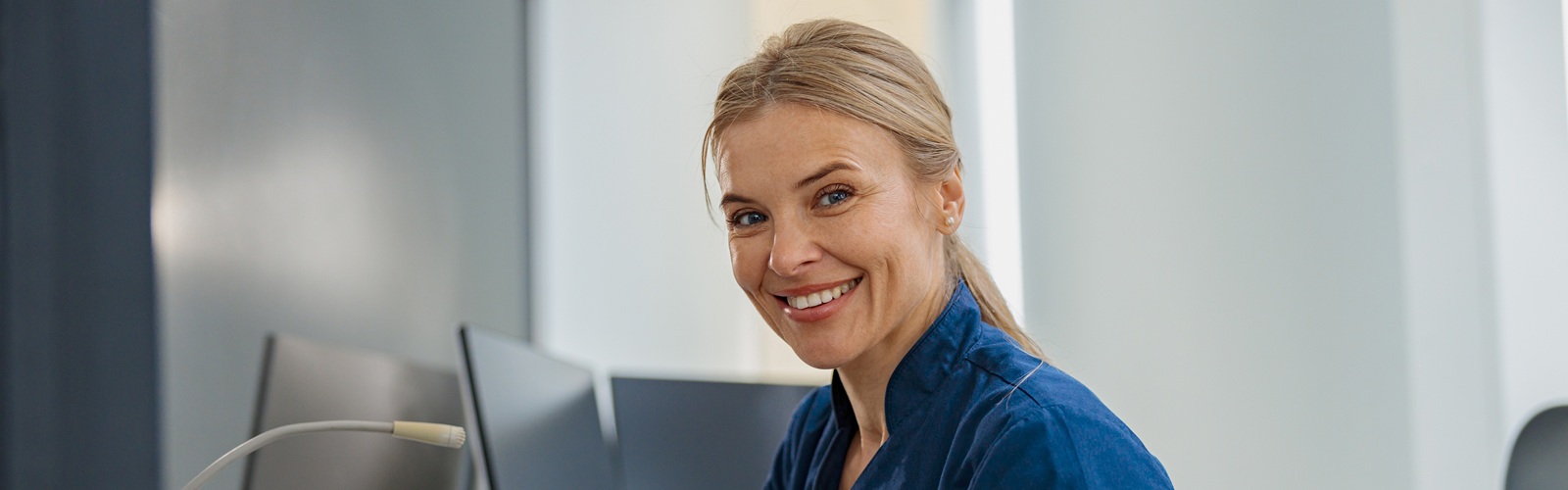 blonde woman sitting at a desk wearing a blue shirt