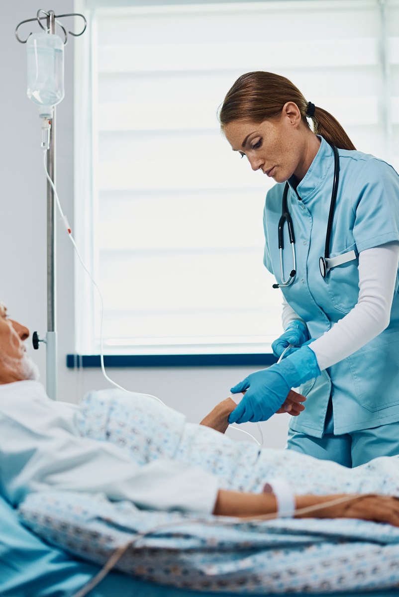 Nurse practitioner drawing a line on a male patient lying in a hospital bed