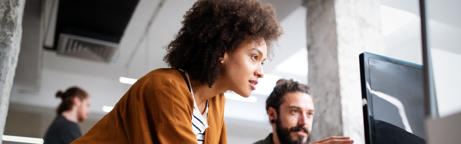 a woman and a man having a discussion as they look at a computer screen together