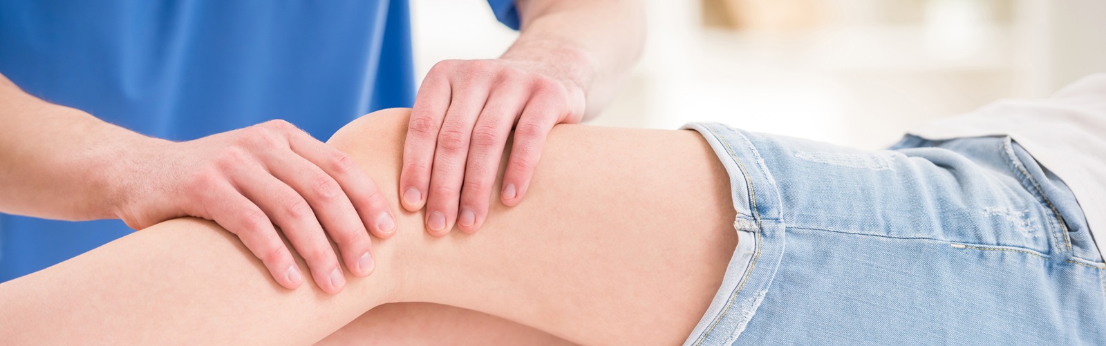 a heathcare worker in blue scrubs is massaing a patient's knee
