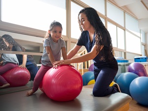 young girl working with a female occupational therapist in a gym setting