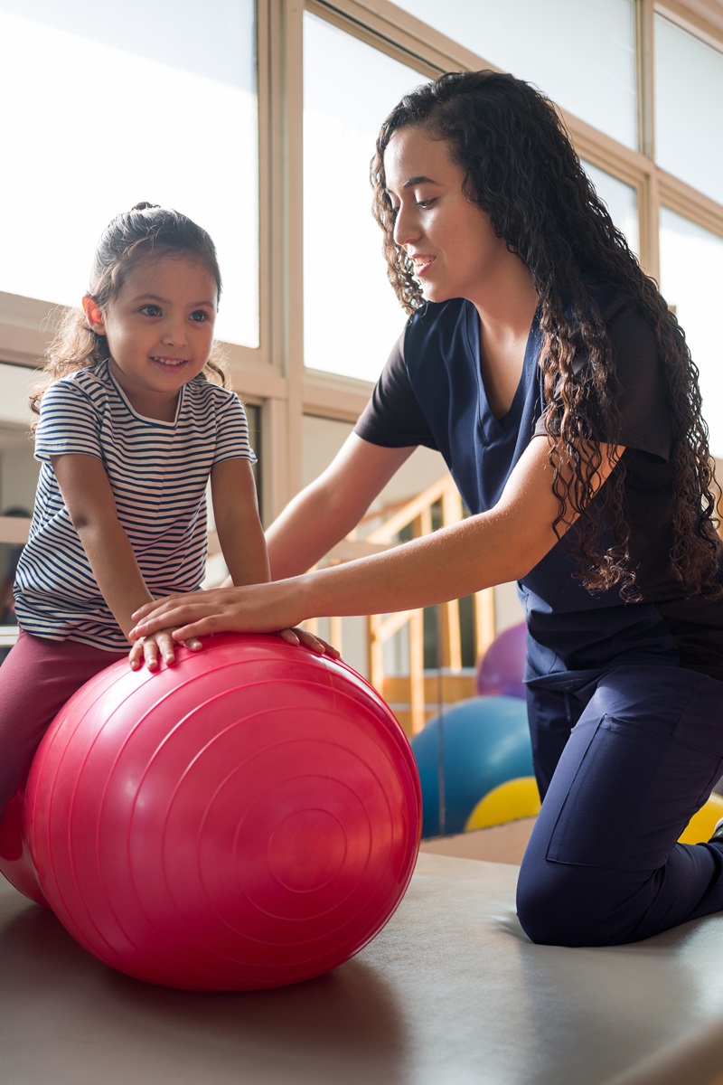 young girl working with a female occupational therapist in a gym setting