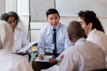 group of professionals, all races, gathered in a circle, having a discussion