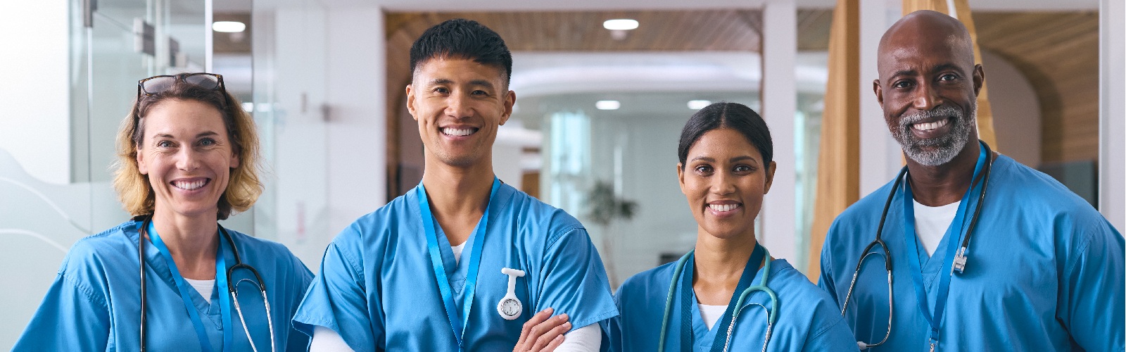 2 women and 2 men in their medical scrubs standing in a hospital hallway
