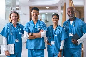 2 women and 2 men in their medical scrubs standing in a hospital hallway