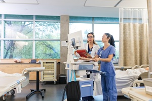 female doctor and nurse looking at a computer in a patient's hospital room