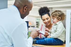pharmacist helping a woman choose a medicine with her small child nearby