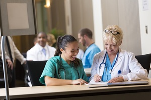 a female doctor and female nursing are looking at a notebook sitting at a long table