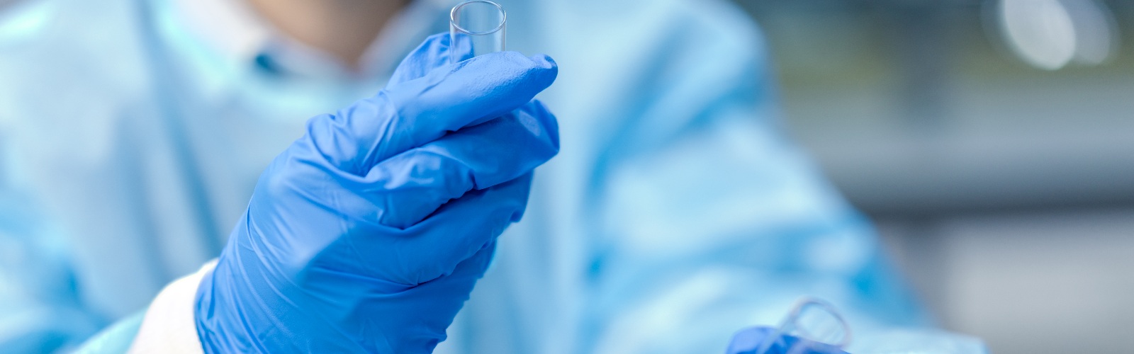 person in medical safety scrubs looking at test tubes