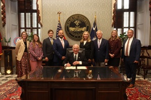 South Carolina Governor signing of a bill with several men and women standing behind the governor at his desk