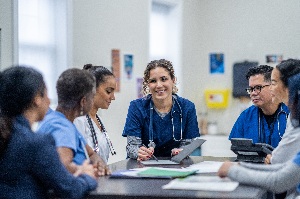 Group of healthcare workers in their scrubrs sitting at a table having a discussion