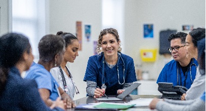 Group of healthcare workers in their scrubrs sitting at a table having a discussion