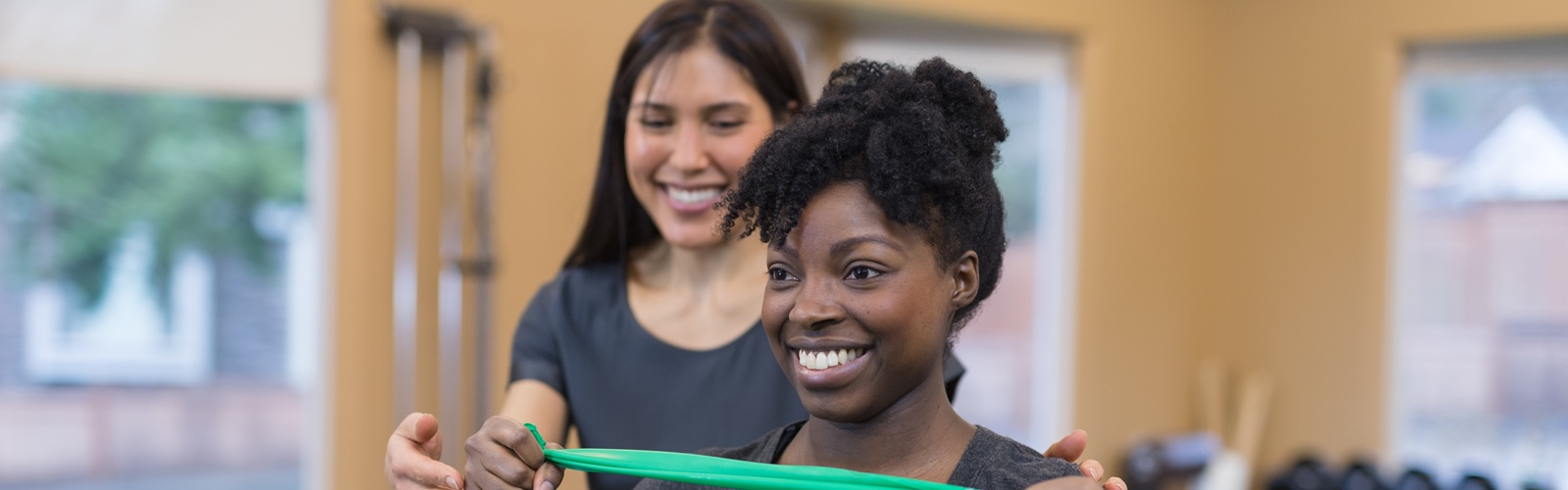 Two women smiling while doing band physical therapy