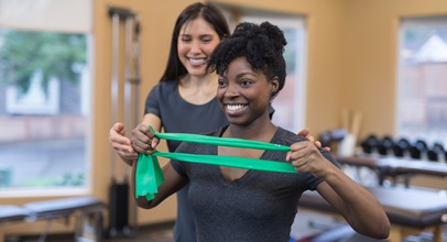 Two women smiling while doing band physical therapy