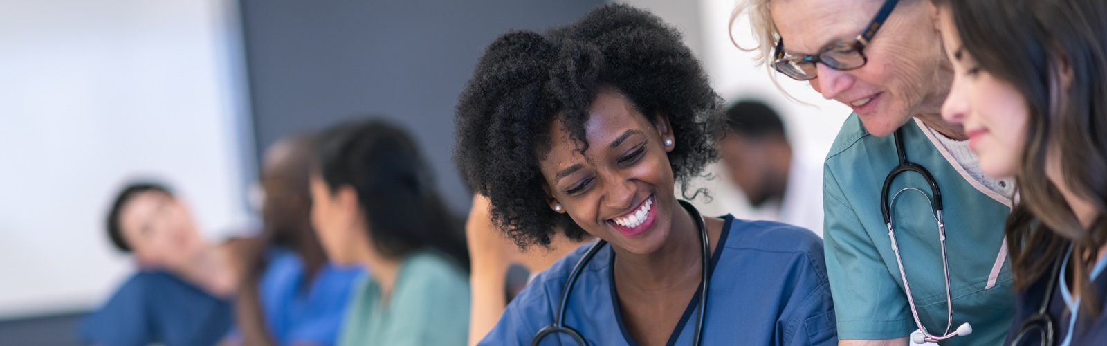 several nursing students in scrubs in a classroom working together