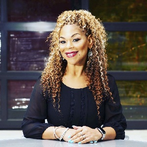 B Christian Randolph posing for a photo at a table wearing a black blouse