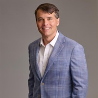 Ben DeGweck headshot in a light suit jacket and white shirt