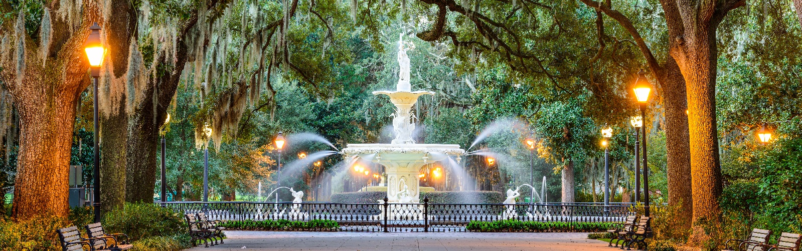 park with street lights on and water flowing from the foundatin
