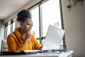 Woman looking at her laptop, considering what to do next