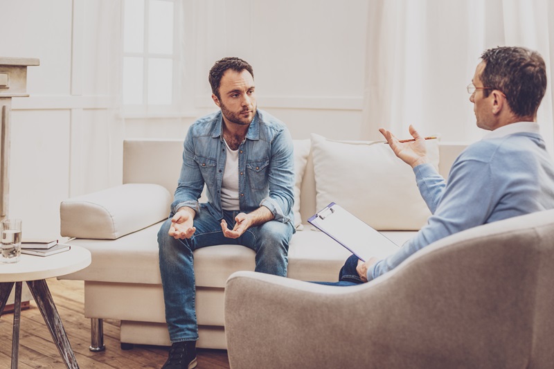 Male psychologist speaking with a patient in an office setting