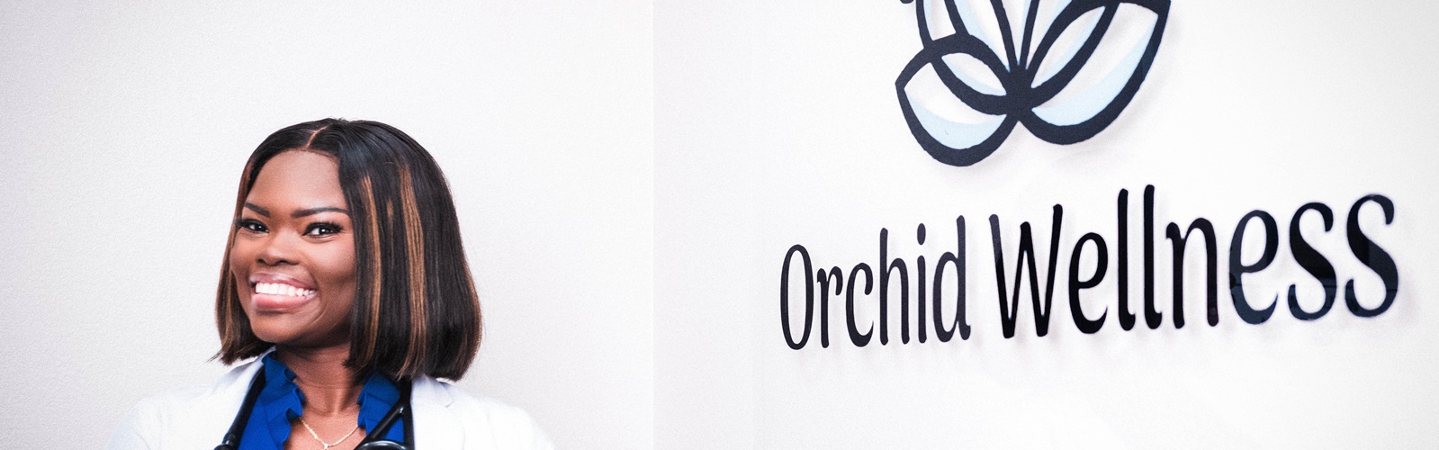 Chelsea Asanta in a white nursing coat and stethoscope posing with the Orchid Wellness sign