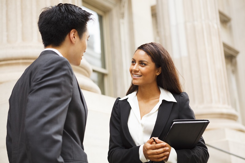 two criminal justice professionals talking standing on the steps of a building