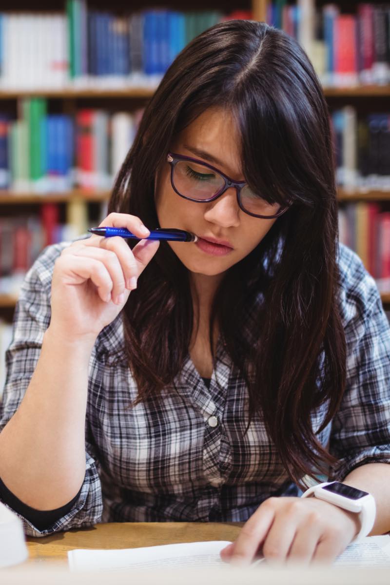 Female student in library reviewing programs