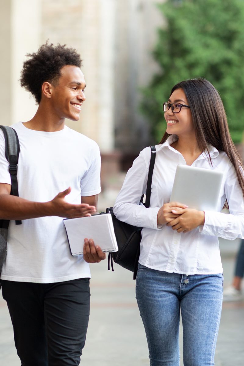 Male and female student talking on college campus