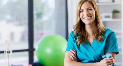 physical therapy assistant holding a set of weights standing in a gym