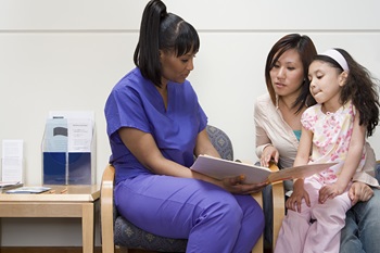 healthcare professional speaking with a mom and daughter in a clinic