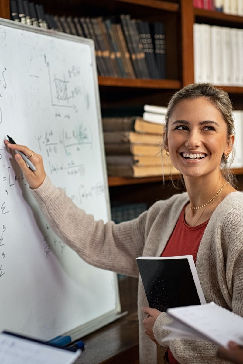 Female student explaining math problems on whiteboard