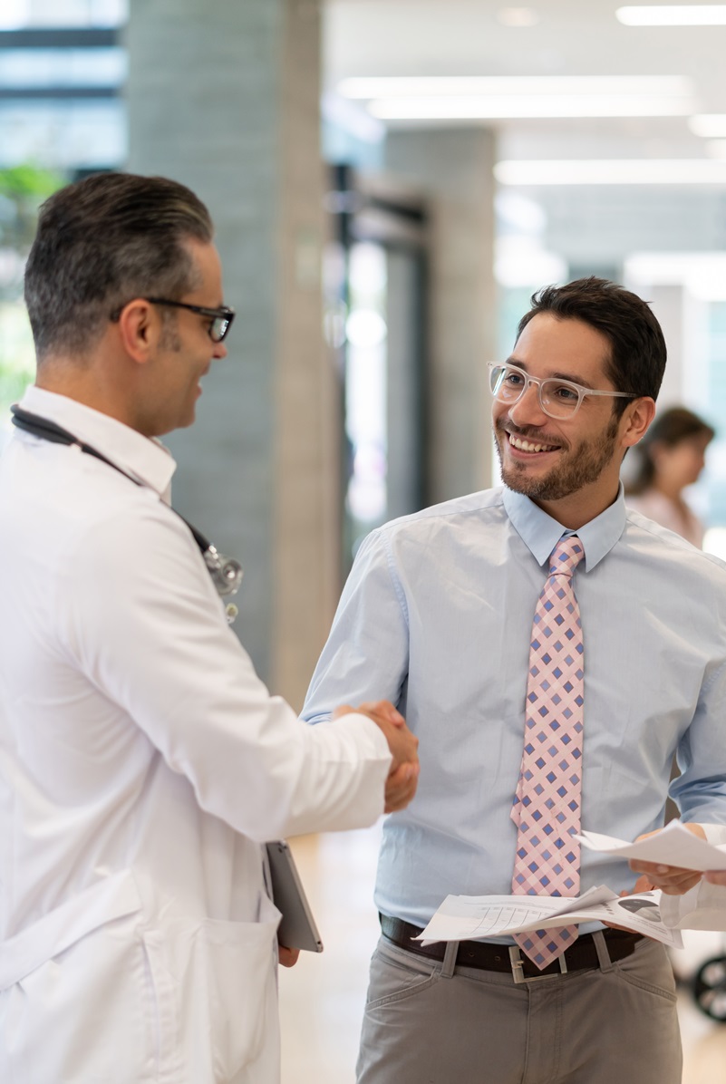 2 male doctors and 1 female doctor discussing healthcare items in a hallway