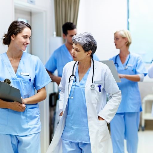 3 female and one male healthcare professionals speaking to each other in a hospital