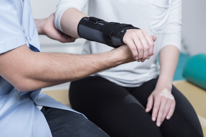 Physical Therapy Assistant assisting a patient with an arm in a cast