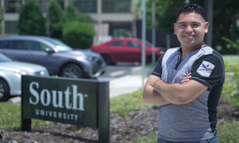 Kemuel Troche standing near a South University sign