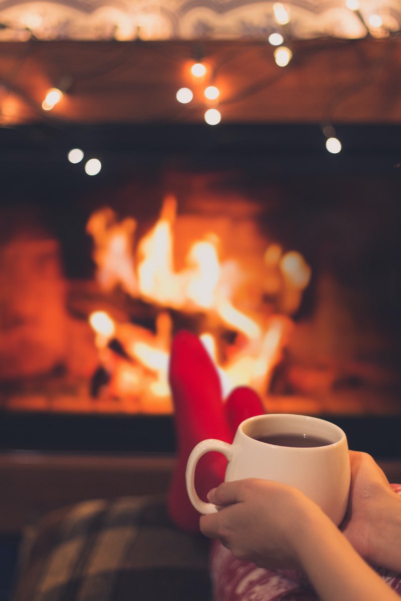 Woman sitting in front of fire drinking tea