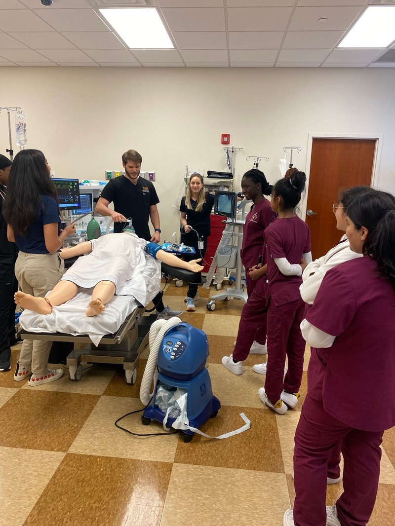 Group of nursing students surrounding a fake patient learning procedures