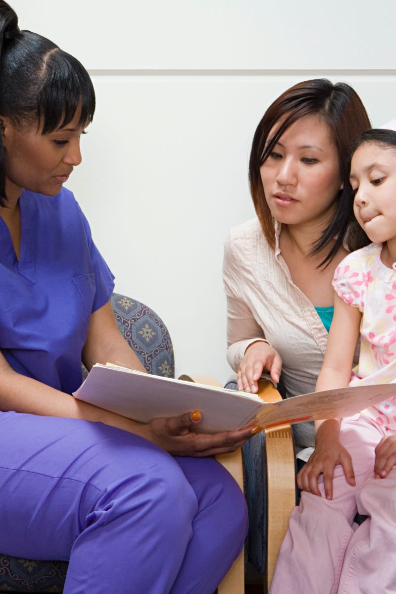 Female nurse consulting mother and child patient