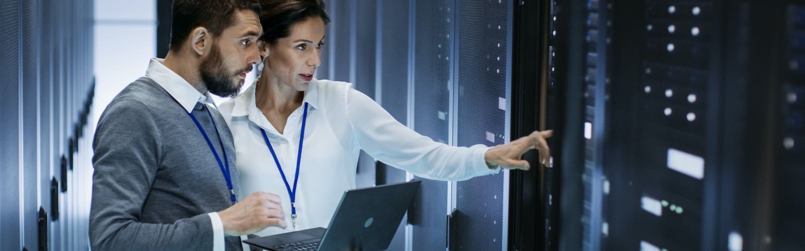 Male and female IT professionals in data center looking at server