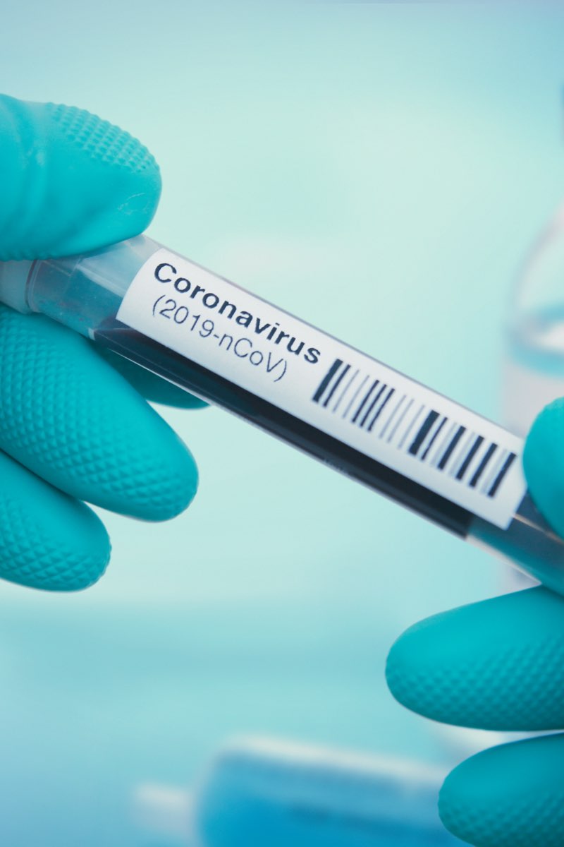 Gloved hands holding coronavirus sample vial in lab