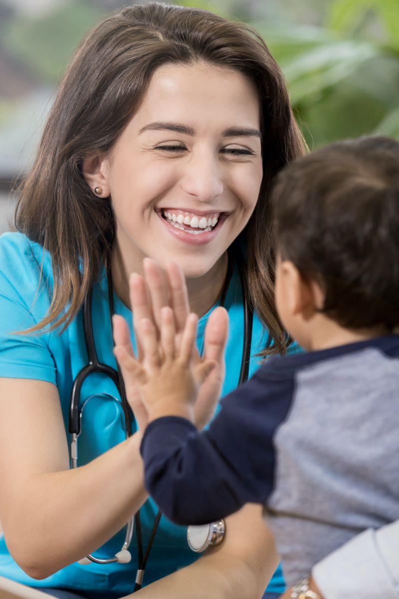 Female nurse smiling with child patient