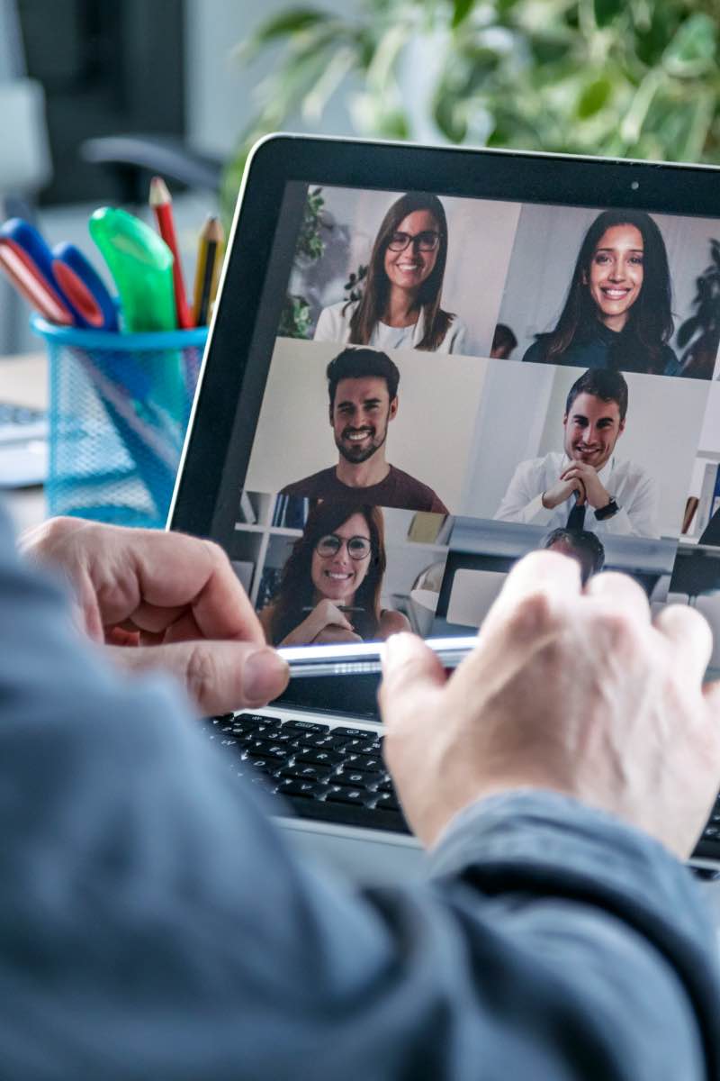 Person working on laptop with coworkers virtually